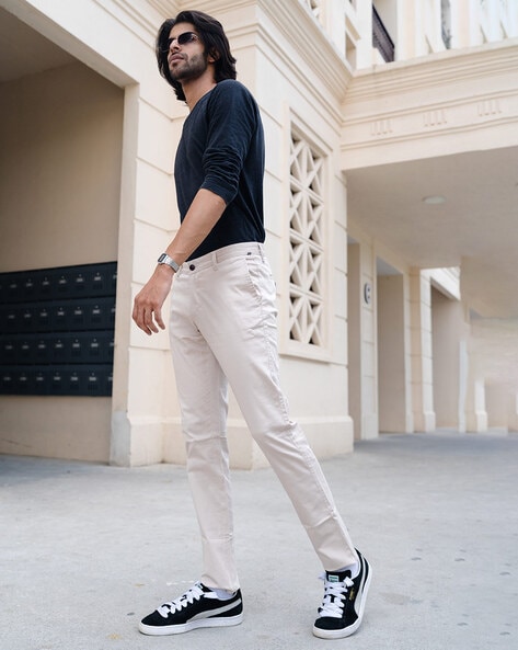 Premium Photo | A woman wearing a white t - shirt and white pants stands  against a green wall.