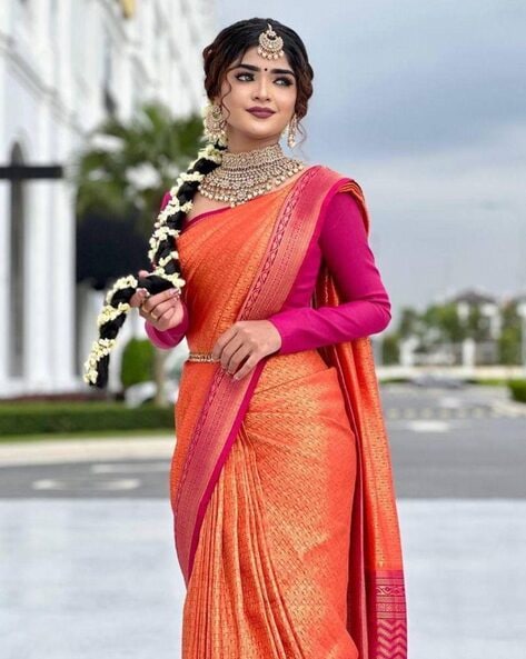 Photo of South Indian bride wearing an orange saree with a purple blouse.