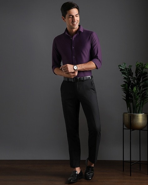 Dressing In A Purple Shirt, Gray Pants And A Black Tie, A Young Handsome  Guy With A Little Beard And Mustache Is Standing By A River, Charmingly  Looking At You. Stock Photo,